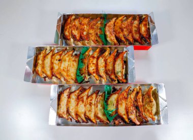 Tamamen altın sarısı tavada kızartılmış gyoza, Asya 'da dayanılmaz bir yemek deneyimi için güzelce paketlenmiş..