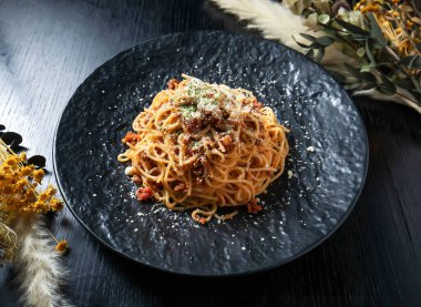 Ağız sulandıran et soslu spagetti ve siyah tabakta parmesan peyniri. Yemek blogları, restoran menüleri veya mutfak reklamları için mükemmel.