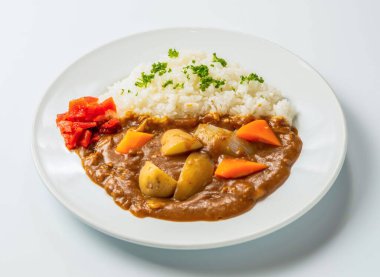 Ağız sulandıran Japon köri yemeği, beyaz arka planda izole edilmiş doyurucu bir yemek için mükemmel, temiz beyaz tabakta haşlanmış pirinç ve taze sebzelerle servis edilir.