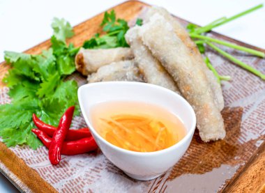 Yeni hazırlanmış börekler otlarla servis ediliyor, Nuoc Cham ve acı biber sosu ahşap tepside yakın çekim görüntüsü.