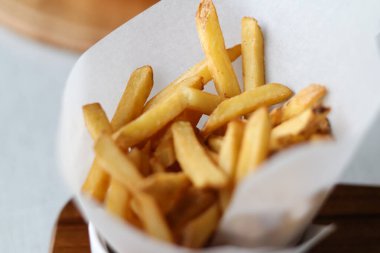 Tahta bir tahtanın üzerinde servis edilen, gevrek altın mantarlı patates kızartmasının tadını çıkar. Sıradan bir yemek deneyimi için mükemmel.