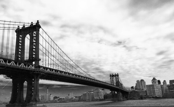 Manhattan bridge cross the city of New York with cloudy sky in black and white style