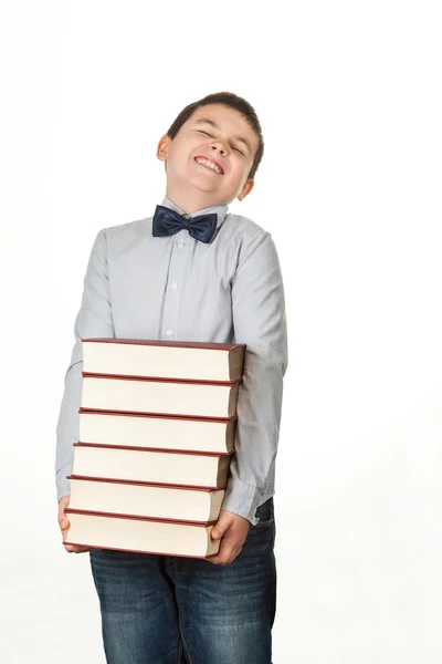 Портрет мальчика, ребенка, расстроенного, держащего шесть тяжелых красных книг — стоковое фото