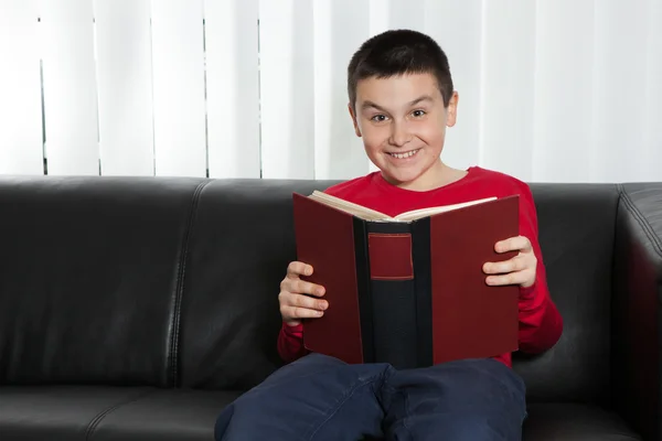 Gelukkige jongen lachend en houden van een boek — Stockfoto