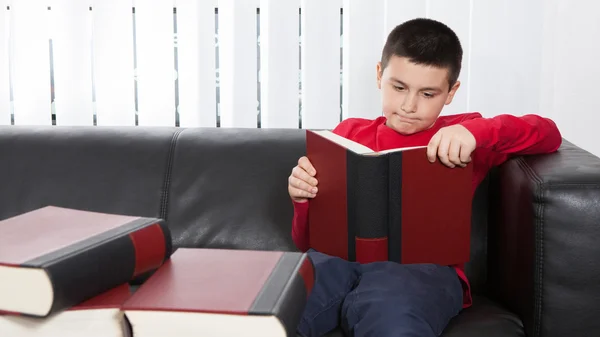 Concentré garçon lecture un livre rouge — Photo