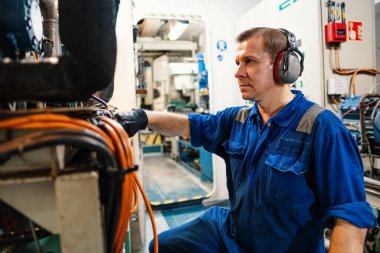 Gemi motorlarını ve itiş gücünü kontrol eden bir deniz mühendisi.