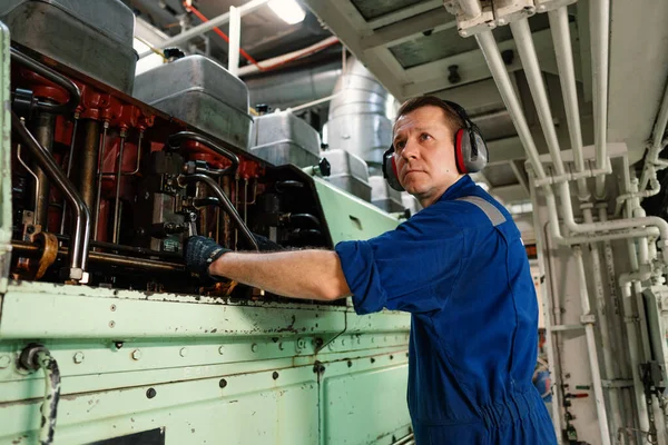 Marine engineer officer controlling vessel enginesand propulsion in engine control room ECR