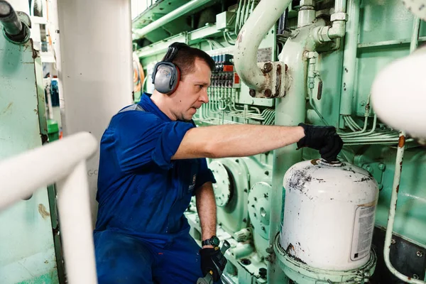 Marine engineer officer controlling vessel enginesand propulsion in engine control room ECR