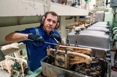 Gemi motorlarını ve itiş gücünü kontrol eden bir deniz mühendisi.