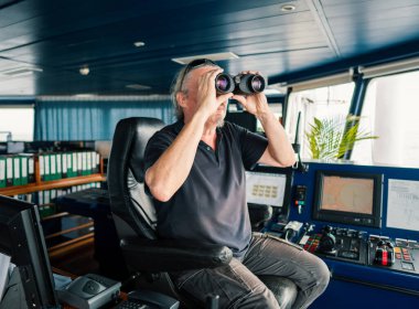 Gemi ya da geminin kaptanı. Dürbünle bakıyor.