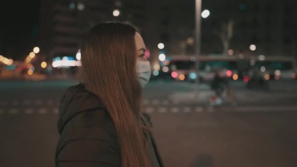 夜間に一人で街を歩く女性モデルは、ウイルス対策マスクを着用. — ストック動画