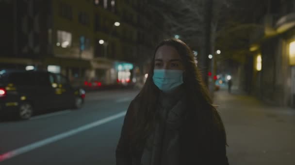 Női modell visel maszkot vírus ellen, séta egyedül az éjszakai városban. — Stock videók