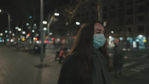 Kobieta modelka w masce przeciw wirusowi, spacerująca samotnie w nocnym mieście. — Wideo stockowe