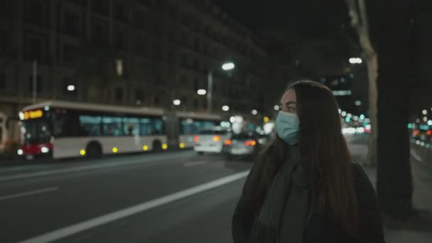 Modello femminile indossando maschera contro il virus, camminando da solo nella città di notte. — Video Stock