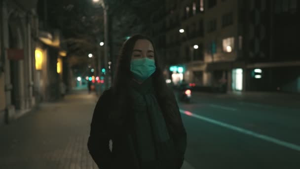 Modello femminile indossando maschera contro il virus, camminando da solo nella città di notte. — Video Stock