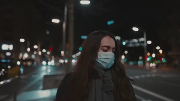Θηλυκό μοντέλο φορώντας μάσκα κατά του ιού, περπατώντας μόνο στην πόλη της νύχτας. — Αρχείο Βίντεο