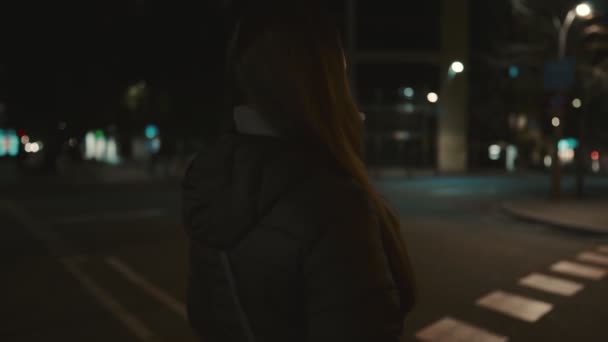 Žena modelka v masce proti viru, kráčí sama v nočním městě. — Stock video