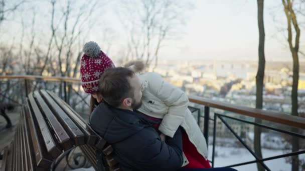 Szczęśliwa romantyczna para ma randkę na ławce w słoneczny zimowy dzień. — Wideo stockowe