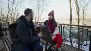 Mutlu romantik çift güneşli kış gününde bankta buluşuyor..