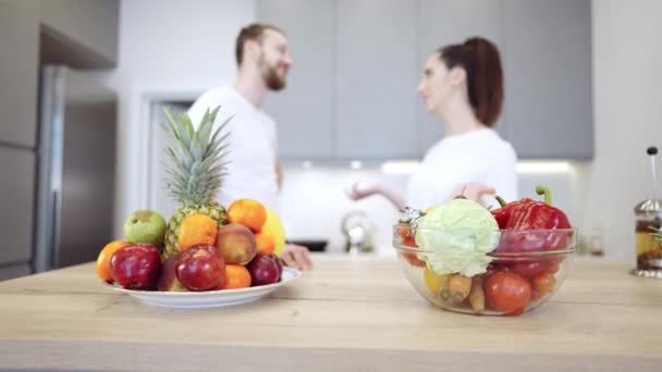 Jovem casal alegre na cozinha discutindo frutas e legumes — Vídeo de Stock