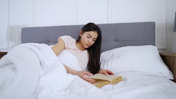 Kvinnan läser en bok på sängen — Stockvideo