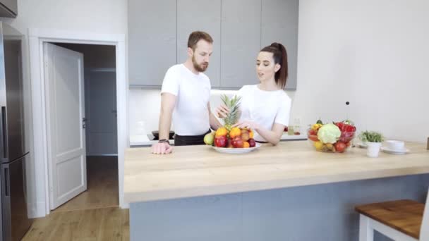 Молода весела пара на кухні обговорюють фрукти та овочі — стокове відео