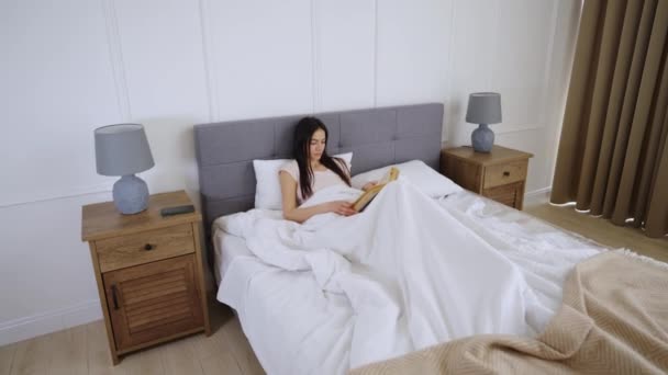 Vrouw leest een boek op bed — Stockvideo