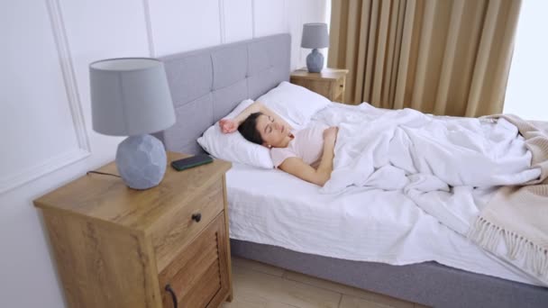 Jonge vrouw slaapt in comfortabel bed — Stockvideo
