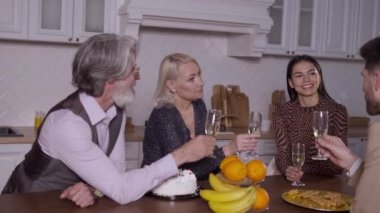 Mutlu bir aile mutfakta oturmuş şampanya içiyor.