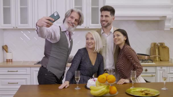 Старший чоловік робить фотографію своєї красивої щасливої сім'ї під час вечірки вдома — стокове відео