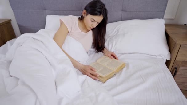 Vrouw leest een boek op bed — Stockvideo