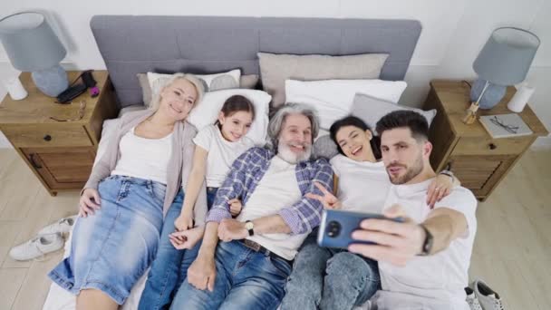 Beautiful happy big family taking selfie while relaxing on bed at home — Stock Video