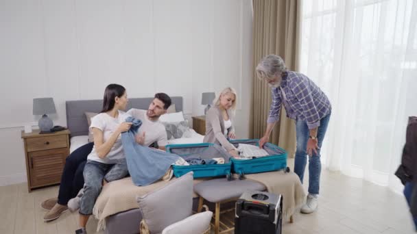 A család segít nagyapának ruhát csomagolni a bőröndbe repülés előtt. — Stock videók