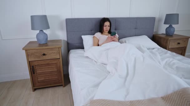 Giovane ragazza si trova a letto con Smartphone — Video Stock