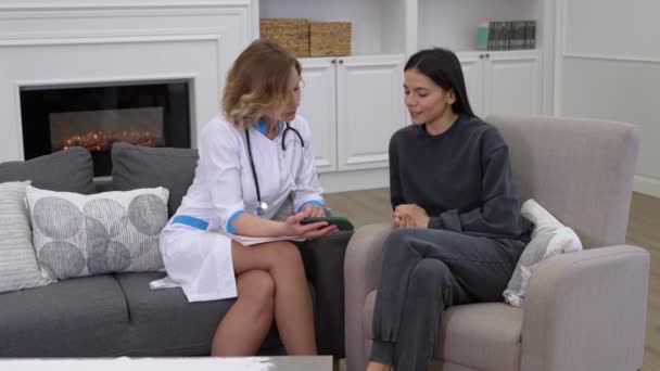 Vrouwelijke arts toont aan de patiënt hoe de gezondheidszorg mobiele app te gebruiken — Stockvideo