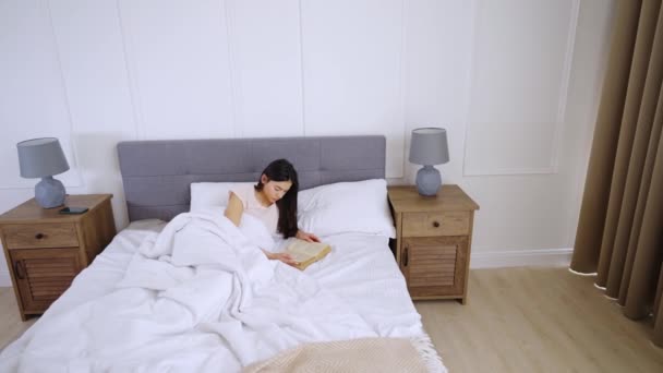 Frau liest Buch auf dem Bett — Stockvideo