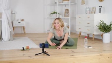Profesyonel yoga eğitmeni online ders verirken takipçilerini selamlıyor