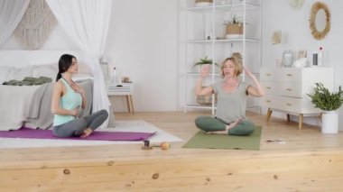 Rahat kadın yoga hocasıyla nefes egzersizi yapıyor.