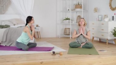 Güzel kadın ve kadın yoga eğitmeni yatak odasında yoga yapıyor.