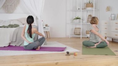 Yoga instructor and client stretching body during home practice