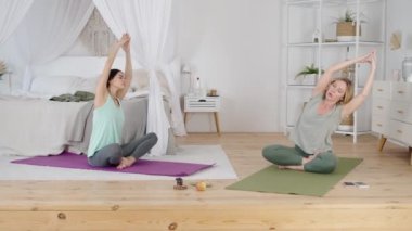 Evde genç bir bayana yoga egzersizleri gösteren profesyonel bir eğitmen.