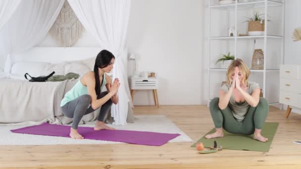 Young woman with instructor finishing yoga practice at home with namaste gesture — Stock Video