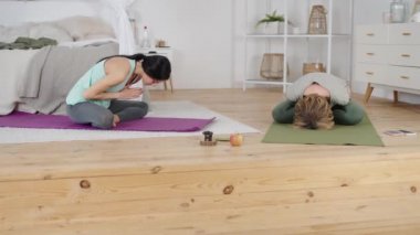 Yoga eğitmeni evde özel ders sırasında genç bir bayanla egzersiz yapıyor.