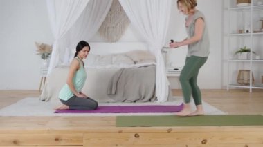 Kadın yoga eğitmeni ve yomg kadını evde özel derse hazırlanıyor.