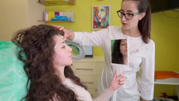 Cosmetologist giving skincare consultation to young woman during appointment in beauty clinic — Stock Video