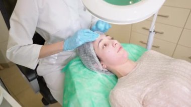 Güzellik uzmanı klinikte cilt bakımı öncesi kadın yüzü hazırlıyor.