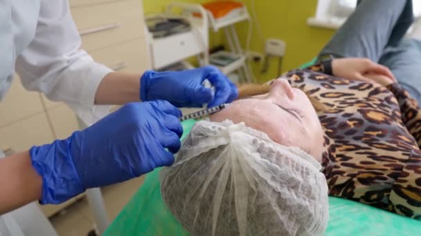Arts injecteren botulinum toxine in het voorhoofd van een vrouw op bezoek schoonheidskliniek — Stockvideo