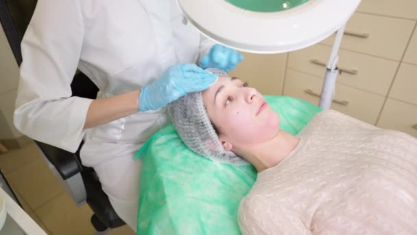 Güzellik uzmanı klinikte cilt bakımı öncesi kadın yüzü hazırlıyor. — Stok video