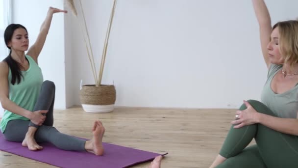 Jovem tentando repetir exercícios de ioga durante a aula particular com o instrutor — Vídeo de Stock