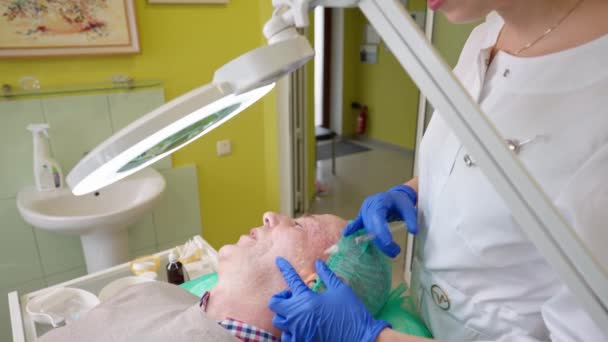 Homem sênior recebendo procedimento de biorevitalização facial na clínica de cosmetologia — Vídeo de Stock